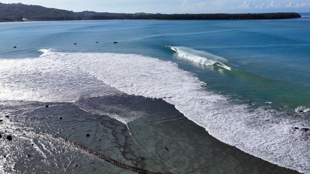 Drone shot looking down on the reef, waves breaking in lines below